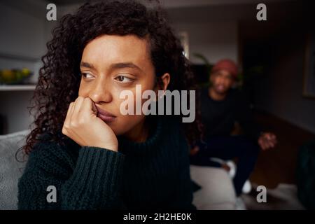 Nahaufnahme einer Frau mit gemischter Rasse, die den schwarzen Freund ignoriert, während sie auf dem Sofa in einer modernen Wohnung kämpft Stockfoto