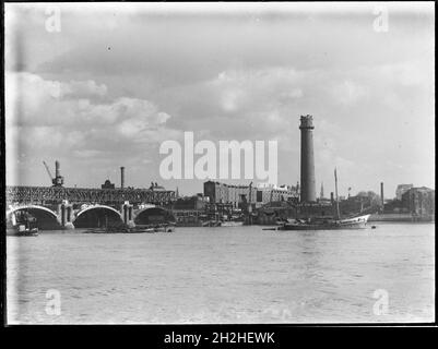 Shot Tower and Lead Works, Belvedere Road, Lambeth, Greater London Authority, 1936. Ein Blick über die Themse in Richtung des Schussturms bei Lambeth Lead Works, der links den Abriss der alten Waterloo Bridge zeigt. Der Schussturm der Lambeth-Hauptwerke wurde von David Ridall Roper entworfen und 1826 für Thomas Maltby &amp; Co. Erbaut. Zum Zeitpunkt dieser Aufnahme wurde er von Walkers, Parker &amp; Co, aber es wurde später im Jahr 1962 abgerissen, um Platz für die Queen Elizabeth Hall zu machen. Die Waterloo-Brücke, die während des Abrisses gezeigt wird, wurde von John Rennie entworfen und eröffnet Stockfoto