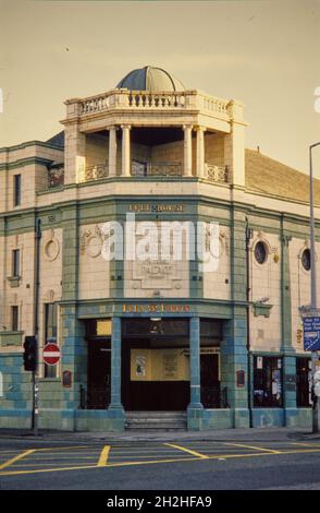 Floh and Firkin Public House, Grosvenor Street, Manchester, 1990-1994. Der Eckeingang des öffentlichen Hauses Flea und Firkin, von Nordwesten aus gesehen, zeigt die grünen Fliesen und die Plakette mit erhöhten Schriftzügen des ursprünglichen Namens des Gebäudes. Der Grosvenor Picture Palace wurde 1915 eröffnet. Ab den 1960er Jahren wurde es für Bingo verwendet, zunächst zusätzlich zu Filmen und später als alleinige Funktion. Es wurde dann zu einem Snooker-Club. Das Gebäude blieb weitgehend unverändert, bis es in ein Pub umgewandelt wurde, das 1990 eröffnet wurde, obwohl ein Großteil des Innenraums intakt bleibt. Stockfoto