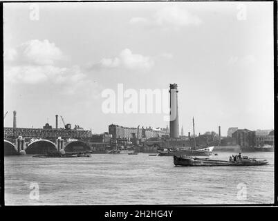 Shot Tower and Lead Works, Belvedere Road, Lambeth, Greater London Authority, 1936. Ein Blick über die Themse in Richtung des Schrotturms bei Lambeth Lead Works, der den Abriss der alten Waterloo Bridge auf der linken Seite und ein Flussboot zeigt, das zur Brücke segelt. Der Schussturm der Lambeth-Hauptwerke wurde von David Ridall Roper entworfen und 1826 für Thomas Maltby &amp; Co. Erbaut. Zum Zeitpunkt dieser Aufnahme wurde er von Walkers, Parker &amp; Co, aber es wurde später im Jahr 1962 abgerissen, um Platz für die Queen Elizabeth Hall zu machen. Die Waterloo-Brücke, die während ihrer Demoli gezeigt wird Stockfoto