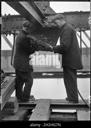 Abriss der Waterloo Bridge, Lambeth, Greater London Authority, 1936. Zwei Männer, die während des Abrisses der alten Waterloo Bridge unter einem Träger arbeiteten. Die Waterloo-Brücke, die während des Abrisses gezeigt wird, wurde von John Rennie entworfen und 1817 eröffnet. Der Abriss der Brücke fand in den 1930er Jahren statt, und die beiden gezeigten Männer demontieren einen provisorischen Stahlrahmen, der 1925 errichtet worden war. Die Brücke wurde später in den 1940er Jahren durch eine andere ersetzt. Stockfoto