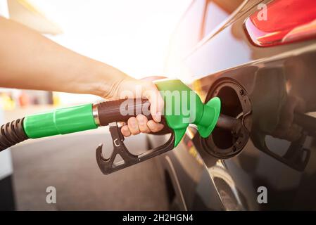 Nahaufnahme der Mann pumpen Benzin im Auto an der Tankstelle. Gas Pumpe Düse in den Kraftstofftank ein graues Auto Stockfoto