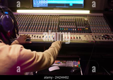 Rückansicht eines jungen Mannes, der im Aufnahmestudio Musik auf Audiogeräten kreide Stockfoto