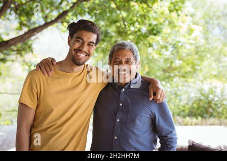 Porträt eines lächelnden, erwachsenen Sohnes und älteren Vaters, der die Kamera anschaut und umarmt Stockfoto