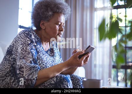 afroamerikanische ältere Frau sitzt und Smartphone benutzt Stockfoto