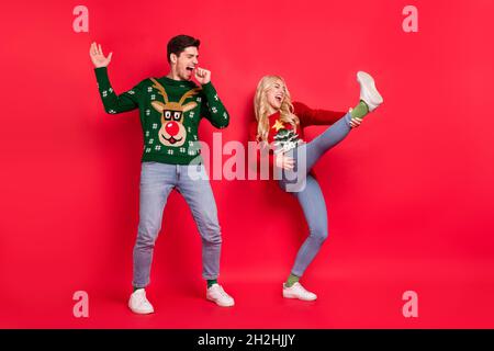 In voller Länge Körpergröße Foto Menschen lachen in hässlichen Jumper vorstellen, auf der Bühne isoliert lebendige rote Farbe Hintergrund Stockfoto