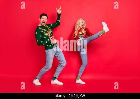 In voller Länge Körpergröße Foto tanzen Menschen lachen in hässlichen Jumper vorstellen Gitarre isoliert lebendige rote Farbe Hintergrund spielen Stockfoto