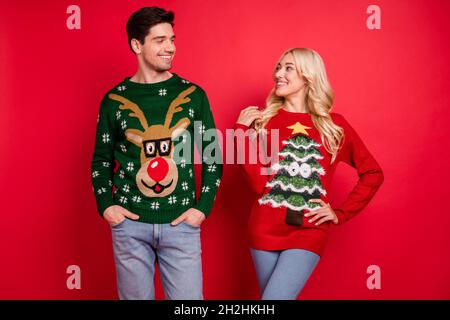 Foto Porträt lächelndes Paar trägt hässliche Pullover feiern Weihnachten isoliert hellen roten Hintergrund Stockfoto