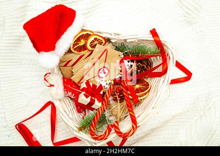 Adventskalender wartet auf Weihnachten. Sammlung von kleinen Bastelumschlägen in einem Korb auf weißem Hintergrund. Saisonale Weihnachtstradition. Stockfoto