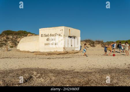 Es Trenc, Spanien; 11 2021. oktober: Alter Bunker des spanischen Bürgerkrieges am Strand von Es Trenc, neben Badegästen, bei Sonnenuntergang. Insel Mallorca, Spanien Stockfoto