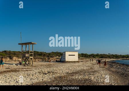 Es Trenc, Spanien; 11 2021. oktober: Alter Bunker des spanischen Bürgerkrieges am Strand von Es Trenc, neben Badegästen, bei Sonnenuntergang. Insel Mallorca, Spanien Stockfoto