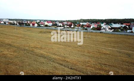 Luftaufnahme des Hüttendorfes in der Nähe des leeren Feldes für zukünftige Gebäude am Ende des Sommers gegen blau bewölkten Himmel. Wunderschöne Landschaft Stockfoto