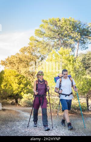 Ein Mann und eine Frau wandern oder wandern durch die Landschaft auf einem Pfad bei Sonnenuntergang Stockfoto