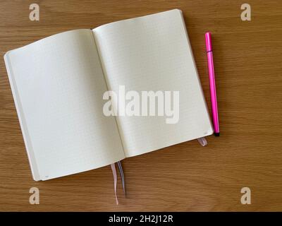 Draufsicht auf ein offenes Notizbuch mit pinkem Bleistift auf dem Schreibtisch Stockfoto