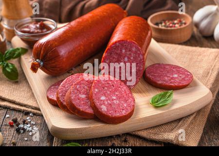 Nahaufnahme der Wurst auf einem Schneidebrett auf einem Holzhintergrund. Seitenansicht, horizontal. Stockfoto