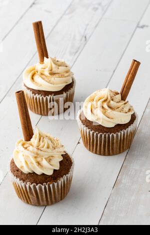 Drei hausgemachte Kürbis-Gewürz-Cupcakes mit Frischkäse-Zuckerguss. Stockfoto