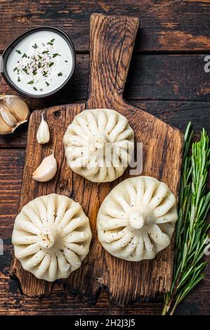 Georgische Krinkali-Knödel mit Rind- und Lammfleisch auf Holzbrett mit Kräutern. Dunkler Holzhintergrund. Draufsicht Stockfoto