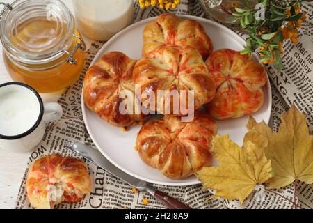 Kürbisbrötchen mit Milch und Honig auf Holzboden Stockfoto