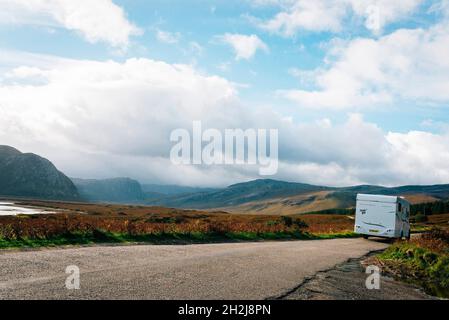 Ein Wohnmobil oder Wohnmobil, das auf einer malerischen Aussicht auf die nc500 Road Trip in schottland mit Seen und Bergen fährt Stockfoto