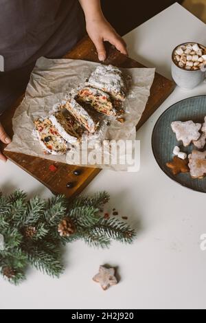 Die Frau serviert Weihnachtsgebäck, Stollen auf einem Holzbrett. Stockfoto