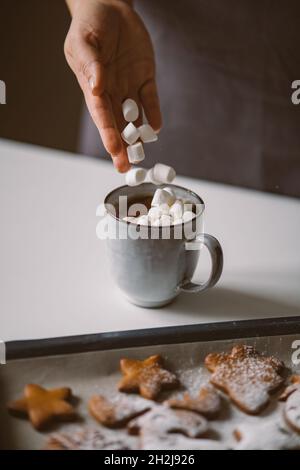 Eine Frau steckt Sümpfe in einen heißen Kakaokrug. Festliche Atmosphäre Stockfoto