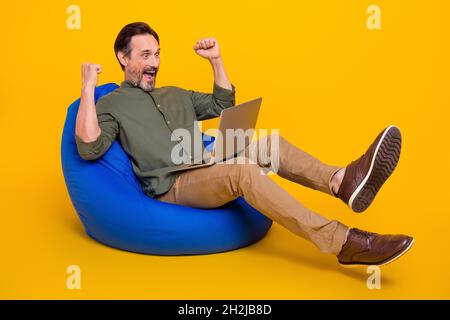 In voller Länge Körpergröße Foto Mann gesturing wie Sieger mit Laptop isoliert lebendige gelbe Farbe Hintergrund Stockfoto