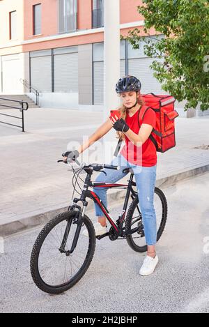 Eine Radfahrerin überprüft die Adresse ihrer nächsten Lieferung mit ihrem Mobiltelefon Stockfoto