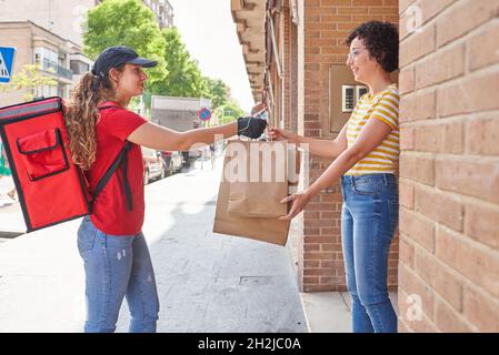 Ein Liefermädchen liefert Beutel mit Lebensmitteln auf die Straße Stockfoto