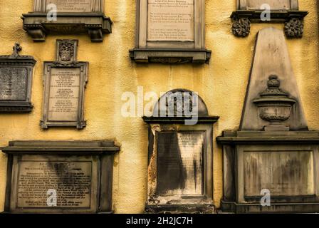 Gelbe Wand von Greyfriar's Kirk, Edinburgh, Schottland, Großbritannien, gesäumt mit historisch reich verzierten geschnitzten Gedenkgräbern und Grabsteinen Stockfoto