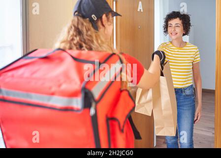 Eine Liefererin liefert einem Kunden eine Lebensmittelbestellung Stockfoto