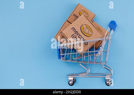 Modifiziertes Foto des Pakets mit Mercado Libre Logo im Warenkorb auf blauem Hintergrund. Stockfoto