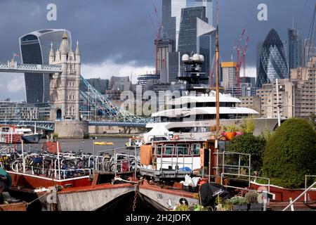 Die Superyacht Kismet dominiert am 20. Oktober 2021 in London, England, die Themse mit ihren traditionellen Lastkähnen und Feuerzeugen im Vordergrund. 'Kismet' ist eine 312 m lange Superyacht, die 2014 gebaut wurde. Es wird vom Charterunternehmen Moran Yacht & Ship verwaltet und gehört dem pakistanisch-amerikanischen Milliardär Shahid Khan. Tower Bridge Moorings ist der einzige schwimmende Garten der Hauptstadt - eine nachhaltige Lebensweise für eine Gemeinschaft von mehr als hundert Erwachsenen und Kindern und ein Schutz für Wildtiere auf dem Fluss. Tower Bridge Moorings ist der einzige schwimmende Garten der Hauptstadt - ein Sus Stockfoto