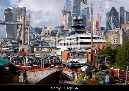 Die Superyacht Kismet dominiert am 20. Oktober 2021 in London, England, die Themse mit ihren traditionellen Lastkähnen und Feuerzeugen im Vordergrund. 'Kismet' ist eine 312 m lange Superyacht, die 2014 gebaut wurde. Es wird vom Charterunternehmen Moran Yacht & Ship verwaltet und gehört dem pakistanisch-amerikanischen Milliardär Shahid Khan. Tower Bridge Moorings ist der einzige schwimmende Garten der Hauptstadt - eine nachhaltige Lebensweise für eine Gemeinschaft von mehr als hundert Erwachsenen und Kindern und ein Schutz für Wildtiere auf dem Fluss. Tower Bridge Moorings ist der einzige schwimmende Garten der Hauptstadt - ein Sus Stockfoto