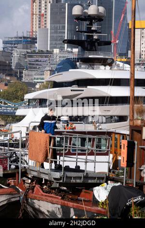 Die Superyacht Kismet dominiert am 20. Oktober 2021 in London, England, die Themse mit ihren traditionellen Lastkähnen und Feuerzeugen im Vordergrund. 'Kismet' ist eine 312 m lange Superyacht, die 2014 gebaut wurde. Es wird vom Charterunternehmen Moran Yacht & Ship verwaltet und gehört dem pakistanisch-amerikanischen Milliardär Shahid Khan. Tower Bridge Moorings ist der einzige schwimmende Garten der Hauptstadt - eine nachhaltige Lebensweise für eine Gemeinschaft von mehr als hundert Erwachsenen und Kindern und ein Schutz für Wildtiere auf dem Fluss. Tower Bridge Moorings ist der einzige schwimmende Garten der Hauptstadt - ein Sus Stockfoto