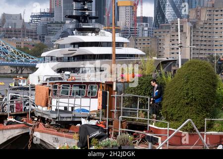 Die Superyacht Kismet dominiert am 20. Oktober 2021 in London, England, die Themse mit ihren traditionellen Lastkähnen und Feuerzeugen im Vordergrund. 'Kismet' ist eine 312 m lange Superyacht, die 2014 gebaut wurde. Es wird vom Charterunternehmen Moran Yacht & Ship verwaltet und gehört dem pakistanisch-amerikanischen Milliardär Shahid Khan. Tower Bridge Moorings ist der einzige schwimmende Garten der Hauptstadt - eine nachhaltige Lebensweise für eine Gemeinschaft von mehr als hundert Erwachsenen und Kindern und ein Schutz für Wildtiere auf dem Fluss. Tower Bridge Moorings ist der einzige schwimmende Garten der Hauptstadt - ein Sus Stockfoto