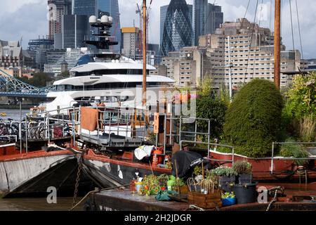 Die Superyacht Kismet dominiert am 20. Oktober 2021 in London, England, die Themse mit ihren traditionellen Lastkähnen und Feuerzeugen im Vordergrund. 'Kismet' ist eine 312 m lange Superyacht, die 2014 gebaut wurde. Es wird vom Charterunternehmen Moran Yacht & Ship verwaltet und gehört dem pakistanisch-amerikanischen Milliardär Shahid Khan. Tower Bridge Moorings ist der einzige schwimmende Garten der Hauptstadt - eine nachhaltige Lebensweise für eine Gemeinschaft von mehr als hundert Erwachsenen und Kindern und ein Schutz für Wildtiere auf dem Fluss. Tower Bridge Moorings ist der einzige schwimmende Garten der Hauptstadt - ein Sus Stockfoto