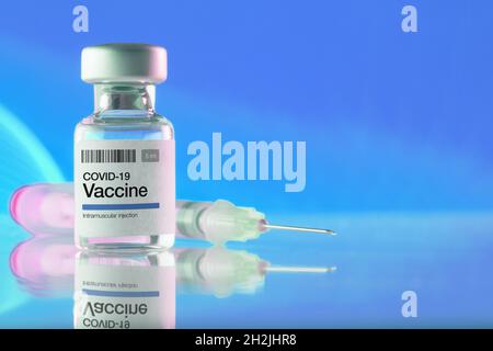 Nahaufnahme eines Fläschchens mit COVID-19-Impfstoff und Spritze auf blauem Hintergrund. Impfungen, Covid-19, Pharmaindustrie und Gesundheitskonzepte Stockfoto