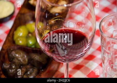 Ein Glas Rotwein an einem Tisch mit Snacks und Fingerfood Stockfoto