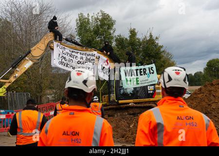 Chalfont St Peter, Großbritannien. Oktober 2021. Stopp HS2-Demonstranten aus dem Kriegslager Wendover aktiver Widerstand besetzten einen Bagger, der heute vor dem Gelände des HS2 Chalfont St Peter Hochwasserschutzarbeiten durchführte, wo die Überschwemmungen auf der Straße angeblich viel schlimmer wurden, seitdem HS2 vor Ort Bäume und Felder geräumt hat. Es wurde berichtet, dass HS2 1,600 Kubikmeter potenziell stark verschmutzenden Bentonits in den Kalkaquifer am Standort verloren hat. Quelle: Maureen McLean/Alamy Live News Stockfoto