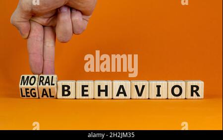 Symbol für moralisches oder rechtliches Verhalten. Geschäftsmann dreht Würfel, ändert Wörter Rechtsverhalten zu moralischem Verhalten. Schöner orangefarbener Hintergrund, Kopierbereich. Psyc Stockfoto