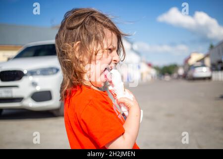 Kaukasische Mädchen essen Eis im Freien heißen Sommertag. Eis schmilzt und fließt Stockfoto