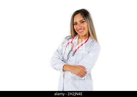 Eine junge Latina-Ärztin mit einem großen Lächeln, die mit gekreuzten Armen und ihrem roten Stethoskop am Hals steht. Konzept der professionellen Frau, er Stockfoto