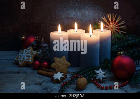 Vier Adventskerzen mit Weihnachtsdekoration, Kugeln und Plätzchen auf rustikalen Holzplanken auf dunkelblauem Hintergrund mit Kopierfläche, ausgewählt fo Stockfoto