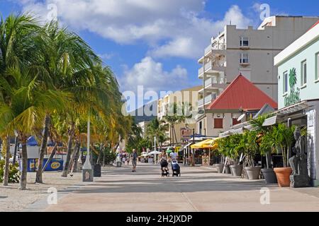 Touristen, die auf einem Boulevard mit Palmen entlang des Strandes in der Hauptstadt Philipsburg der niederländischen Insel Sint Maarten in der Karibik spazieren Stockfoto