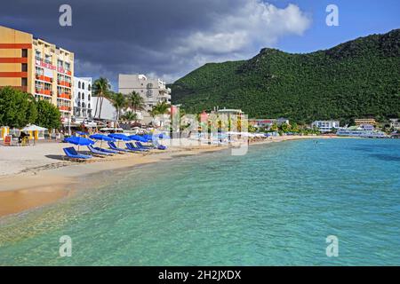 Touristen sonnen sich am Sandstrand mit Palmen an der Great Bay in der Hauptstadt Philipsburg des niederländischen Inselteils Sint Maarten in der Karibik Stockfoto