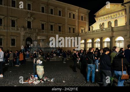 Rom, Italien - Oktober 10 2021: Müllbeutel voller Müll bei Trastevere. Müll draußen transparenten Müllcontainer auf einem öffentlichen Platz der römischen Hauptstadt mit Menschenmassen vor beleuchteten Basilika unserer Lieben Frau in der Nacht Stockfoto