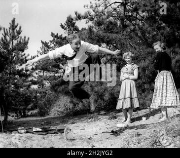 Junger Mann beeindruckte die Mädchen durch einen Sprung in die Luft Großbritannien 1950 Stockfoto