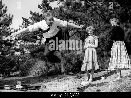 Junger Mann beeindruckte die Mädchen durch einen Sprung in die Luft Großbritannien 1950 Stockfoto