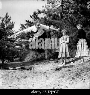 Junger Mann beeindruckte die Mädchen durch einen Sprung in die Luft Großbritannien 1950 Stockfoto