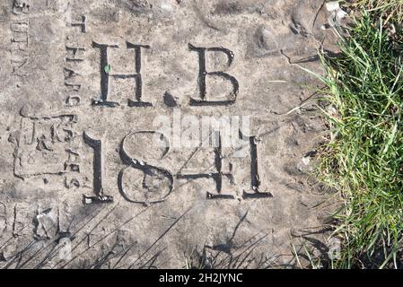 Namen und Daten, die am Fuß des Fahnenmastes, der sich auf dem Gipfel des Castlebergh Hill in Settle befindet, in Stein gemeißelt sind Stockfoto